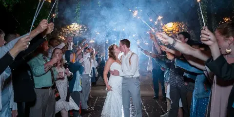 Bride and groom kissing during a sparkler send-off at a wedding reception.