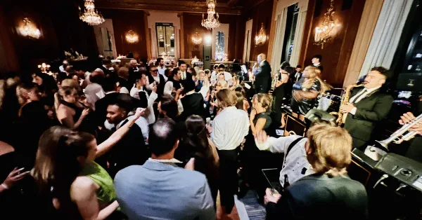 A live band performing on stage at a wedding reception with a crowded dance floor.