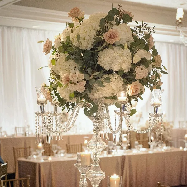 Elegant floral centerpiece with white hydrangeas and pink roses on a crystal candelabra stand in a banquet hall.