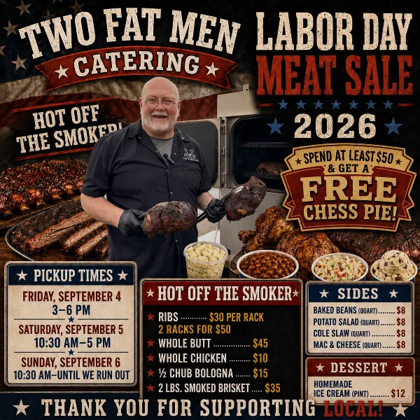 A man in a black shirt holding two pieces of smoked meat in front of a smoker and a table of catering food.