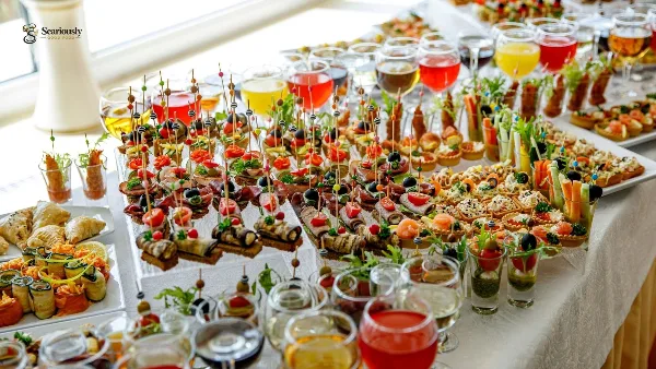 A long table filled with an assortment of catering appetizers, skewers, and drinks.
