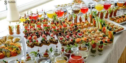 A long table filled with an assortment of catering appetizers, skewers, and drinks.