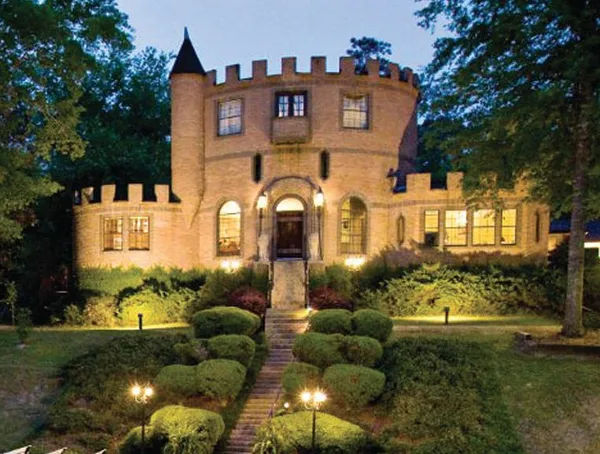 Exterior view of the Louisiana Castle wedding venue at dusk, featuring a stone tower, crenellated walls, and illuminated windows.