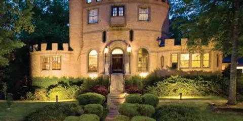 Exterior view of the Louisiana Castle wedding venue at dusk, featuring a stone tower, crenellated walls, and illuminated windows.
