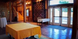 Interior view of a rustic wooden barn event venue with a staircase and tables set up for an event.
