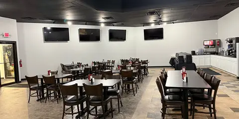 Interior view of a catering business dining area with tables, chairs, and a beverage station.