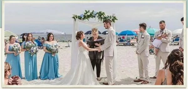 A wedding ceremony taking place on a beach with a bride, groom, officiant, and wedding party.
