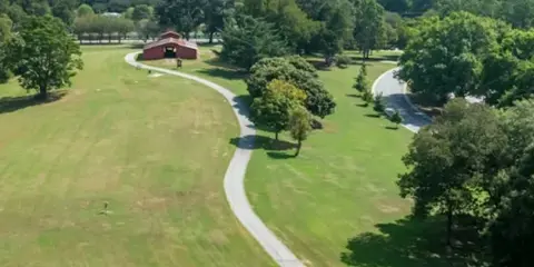 Aerial view of a large green lawn with a gazebo and paved pathways, representing the outdoor grounds of a venue.