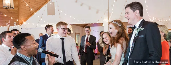 A bride and groom laughing and interacting with guests and a microphone at a wedding reception.