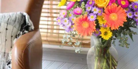 Colorful mixed bouquet in a clear glass vase on a side table