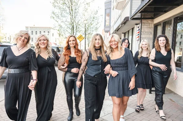 A group of eight women, the salon's staff, posing together outside the storefront.