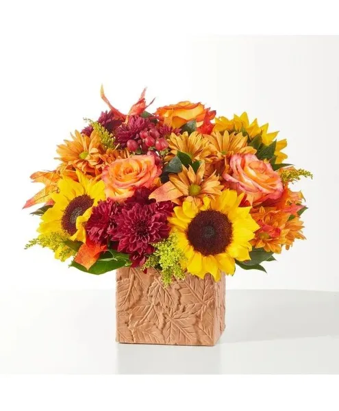 A floral arrangement with sunflowers, roses, and chrysanthemums in a textured vase.
