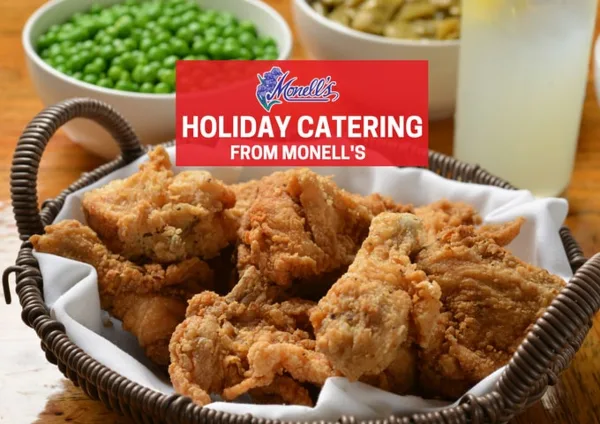 Basket of fried chicken with bowls of green peas and green beans and a glass of lemonade on a wooden table.