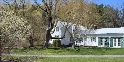 Exterior view of the Landis Arboretum building with green shutters and surrounding trees