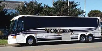 A white and black Discovery Charters motorcoach parked outdoors.