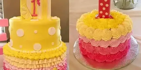 A two-tiered yellow and pink custom cake with ruffled frosting and a lemonade sign, next to a smaller pink and yellow cake with a number 1 candle.