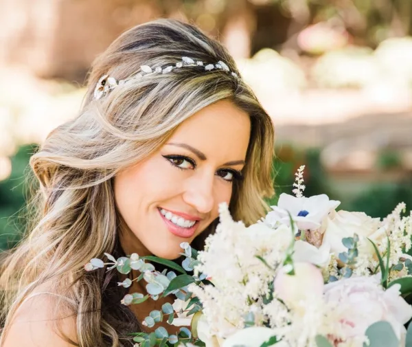 Bride with styled hair and makeup holding a white floral bouquet