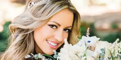 Bride with styled hair and makeup holding a white floral bouquet