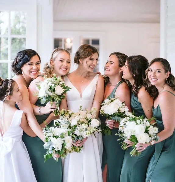 A bride and her bridesmaids posing together, showcasing styled hair and makeup.