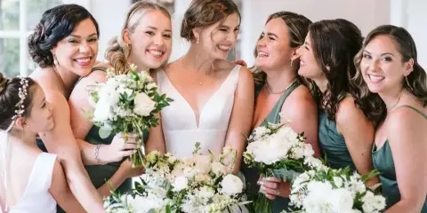 A bride and her bridesmaids posing together, showcasing styled hair and makeup.