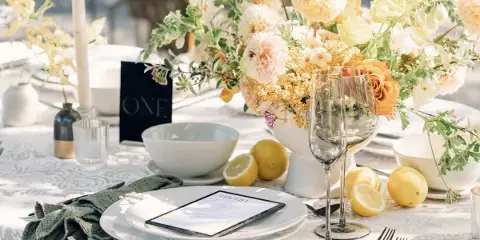 Elegant wedding table setting featuring a floral centerpiece, white plates, wine glasses, and lemons.