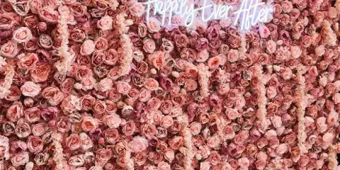 A large pink floral wall backdrop featuring a 'Happily Ever After' neon sign.