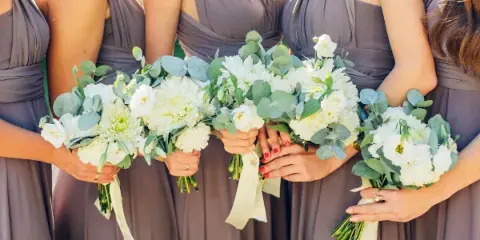 Bridesmaids in gray dresses holding white and green wedding bouquets