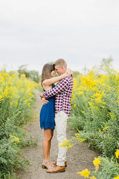 A couple embracing in a field of yellow flowers during an outdoor engagement session.