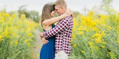 A couple embracing in a field of yellow flowers during an outdoor engagement session.