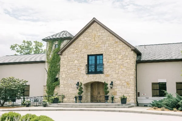 Exterior view of the Silver Oaks Chateau stone building with a central arched wooden entrance and ivy-covered tower.