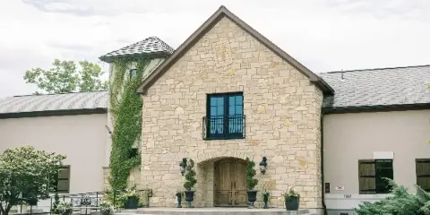 Exterior view of the Silver Oaks Chateau stone building with a central arched wooden entrance and ivy-covered tower.