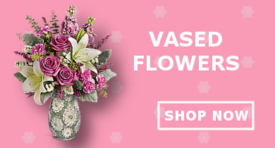 A floral arrangement featuring pink roses and white lilies in a decorative vase.
