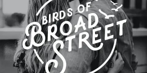 Black and white photograph of a couple embracing with the Birds of Broad Street logo overlaid.