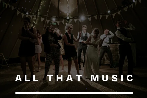A bride and wedding guests dancing at a reception under string lights and bunting.