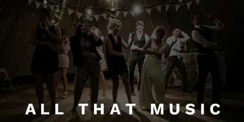 A bride and wedding guests dancing at a reception under string lights and bunting.
