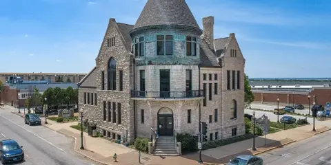 Exterior view of the John Wood Mansion, a historic stone building with a conical turret, located on a street corner.