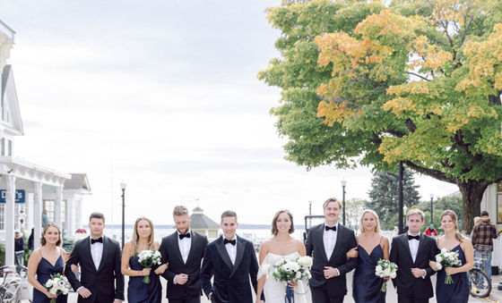 Wedding party posing outdoors with the bride and groom holding white bouquets.