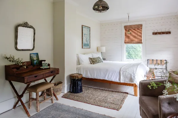Interior of a guest room at Foxfire Mountain House featuring a wooden bed, white linens, and rustic furniture.