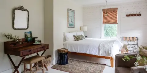 Interior of a guest room at Foxfire Mountain House featuring a wooden bed, white linens, and rustic furniture.
