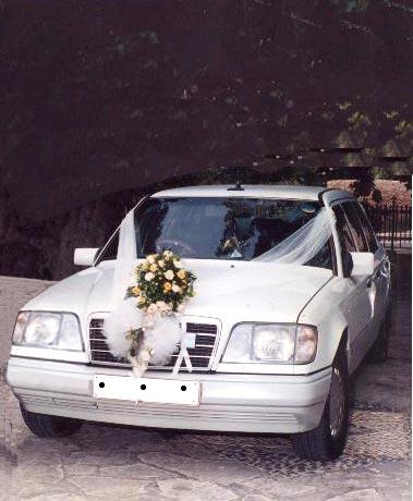 White luxury sedan decorated with a floral arrangement and ribbons