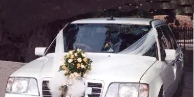 White luxury sedan decorated with a floral arrangement and ribbons