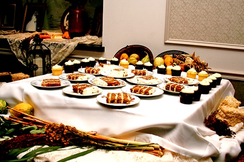 A catering table set with multiple plates of appetizers, pastries, and desserts.