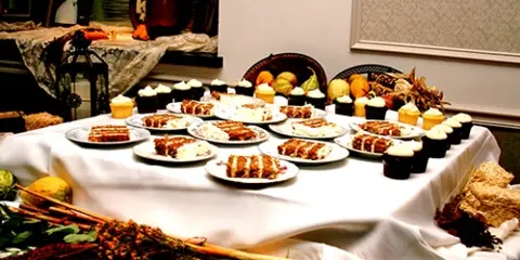 A catering table set with multiple plates of appetizers, pastries, and desserts.
