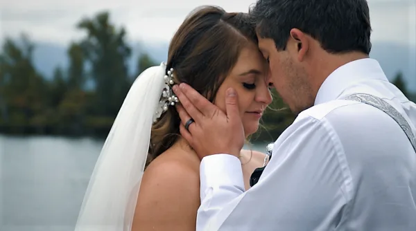 A close-up of a bride and groom sharing an intimate moment outdoors near a body of water.