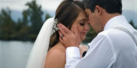 A close-up of a bride and groom sharing an intimate moment outdoors near a body of water.