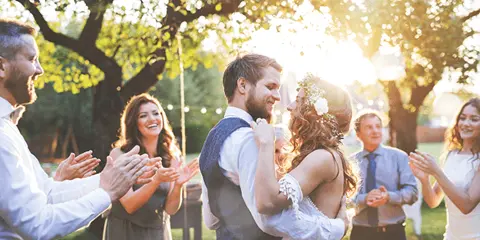A bride and groom dancing at an outdoor wedding reception while guests applaud.