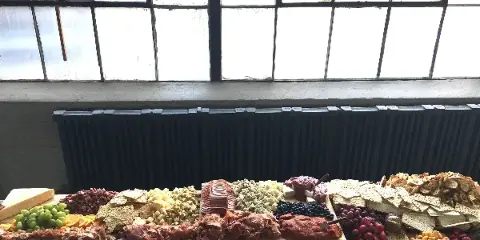 A long table display of charcuterie, cheeses, crackers, nuts, and fresh fruit arranged for a catering event.