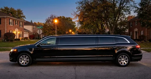 A black stretch limousine parked on a residential street at dusk.