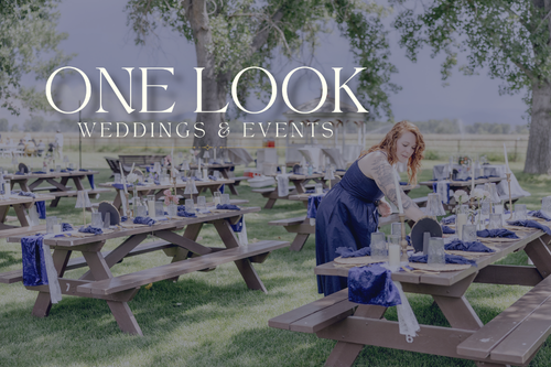 A wedding planner in a blue dress arranging table settings at an outdoor event.