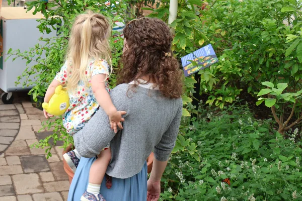 A woman holding a young child viewing plants inside the Buffalo and Erie County Botanical Gardens conservatory.